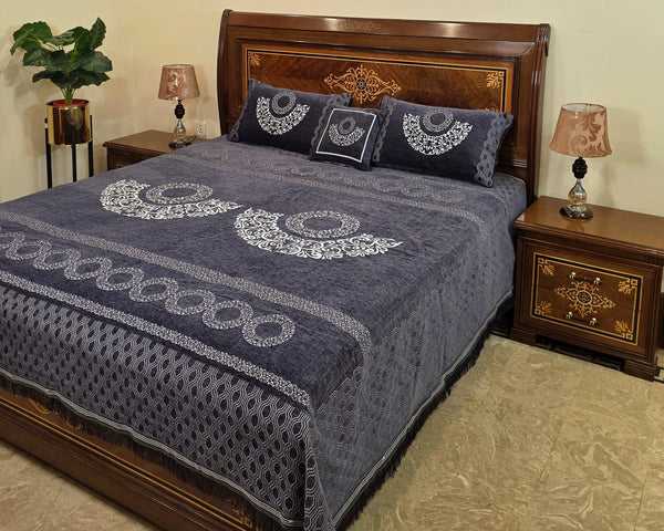 Bed with blue patterned cover and wooden headboard in a bedroom setting.