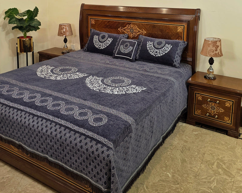 Bed with blue patterned cover and wooden headboard in a bedroom setting.