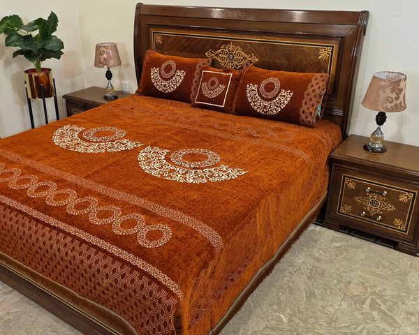 Decorative brown bedspread with intricate patterns on a bed in a room.