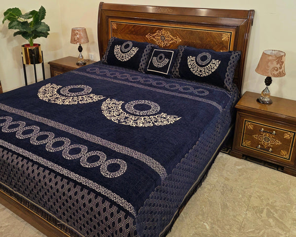 Navy blue quilt with white patterns on a bed in a bedroom setting.