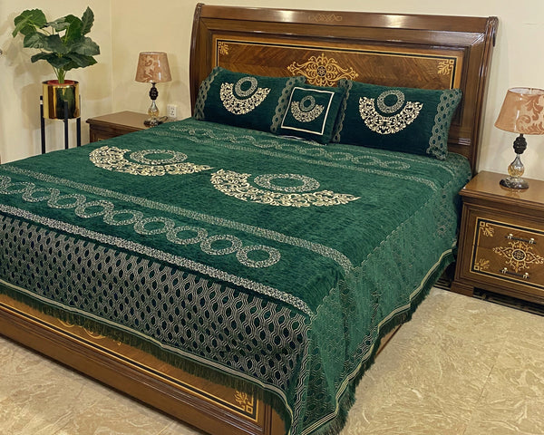 Decorative green bedspread with intricate patterns on a wooden bed in a bedroom setting.